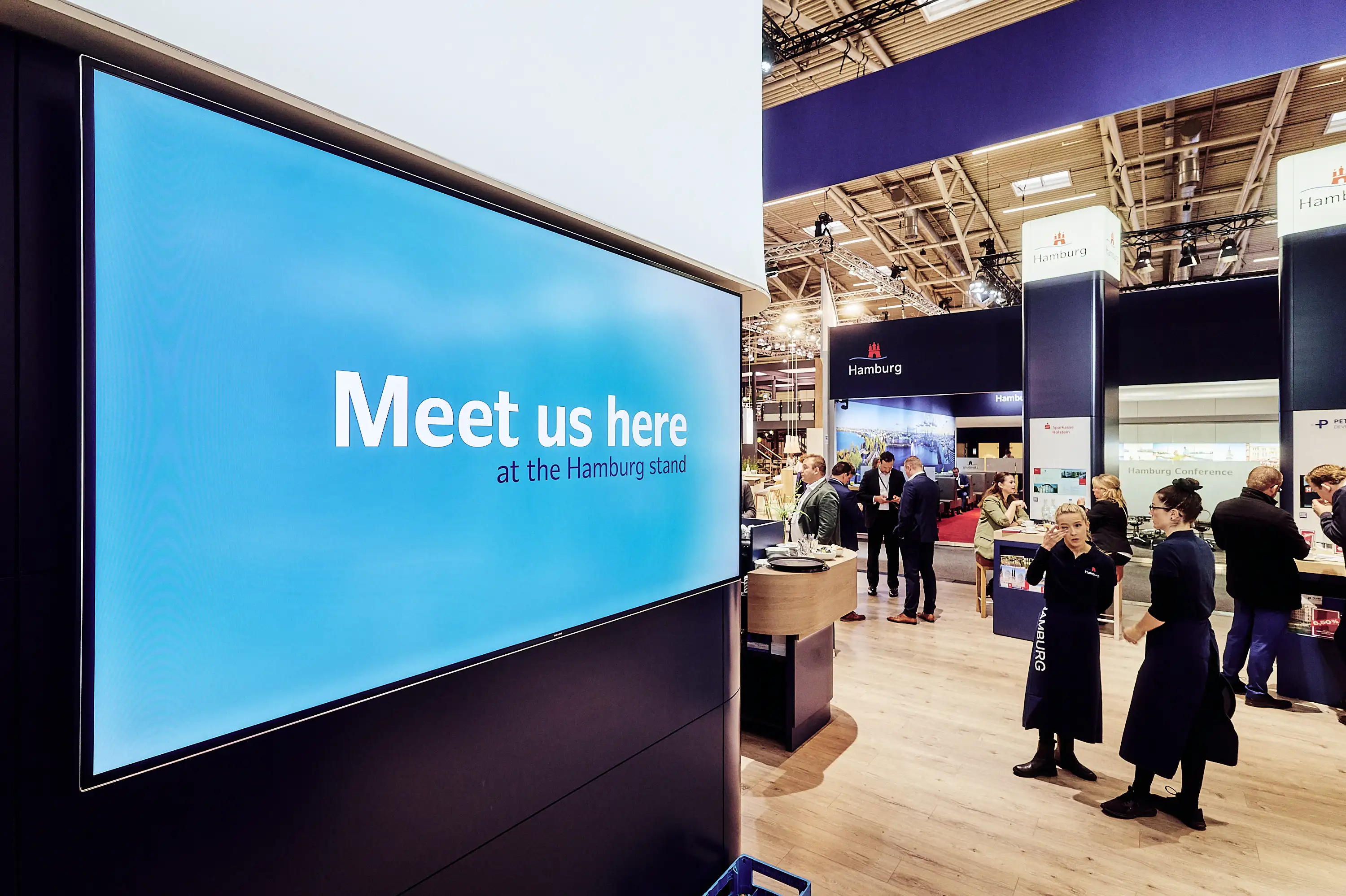 Large blue display with Meet us here text at EXPO REAL.