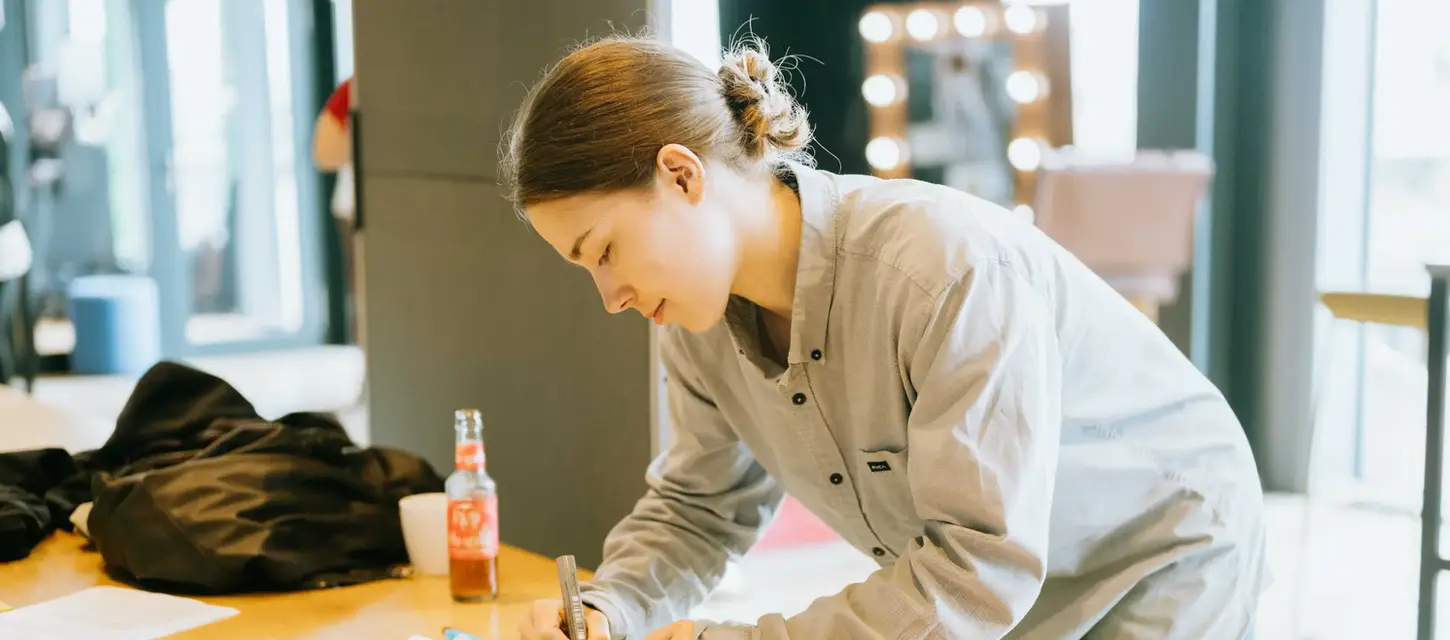 Junge Frau konzentriert sich auf Handarbeit am Tisch mit Bastelzubehör.