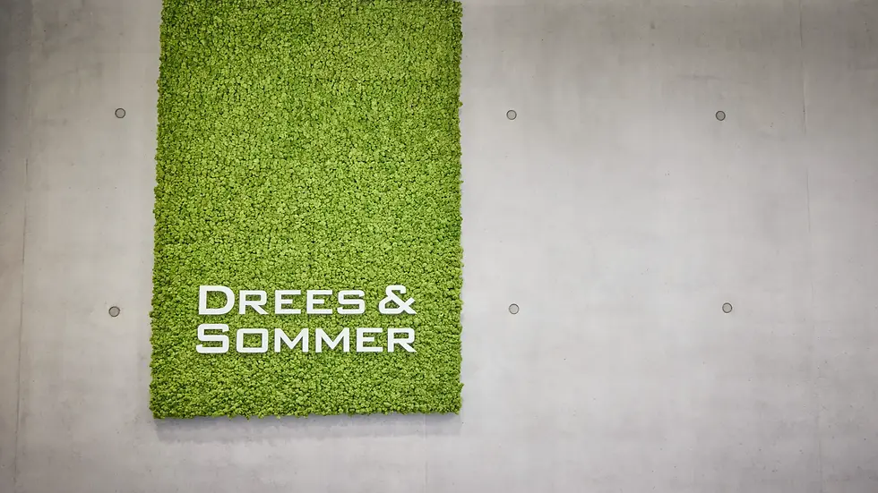 Firmenlogo „Drees & Sommer“ auf einer grünen Mooswand vor Betonhintergrund.