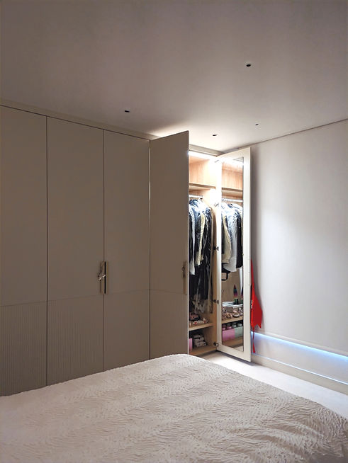 white detailed doors of bespoke fitted wardrobe with door open, integrated lighting, hanging rail and shelf