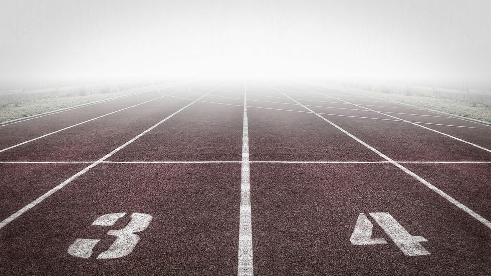 Vista de una pista de atletismo con líneas blancas marcadas y los números 3 y 4 visibles en primer plano, desvaneciéndose en la niebla en el horizonte.