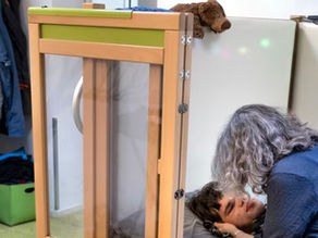 Een jongen met een ernstige verstandelijke beperking in een hoog/laag bed. Zijn moeder zit naast hem en er is ook een rolstoel zichtbaar