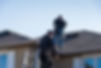 Two roofers inspecting a damaged roof.jp