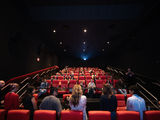 Audience members seated in a theater watching a Q&A session, with attention directed toward the front of the room.