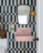 Bathroom with green and white checkered tiles, pink sink, gold faucet, oval mirror, and hanging lamp. Rustic vase with branches adds charm.