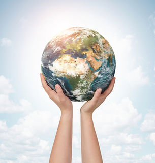 Hands holding up a realistic Earth against a bright, cloudy sky, symbolizing care, unity, and global connection.
