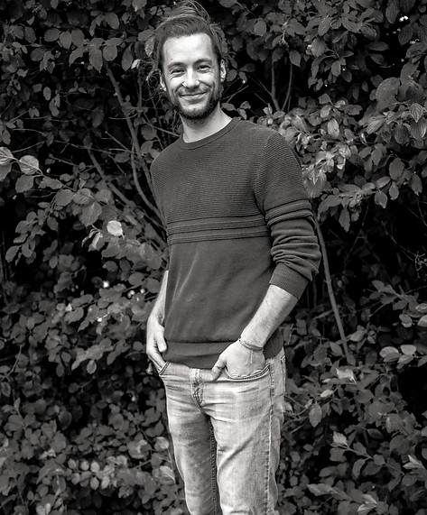 Michel standing in front of a bush with a smile.