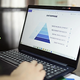 A circular image of a person typing on a laptop with a pyramid chart on the screen.