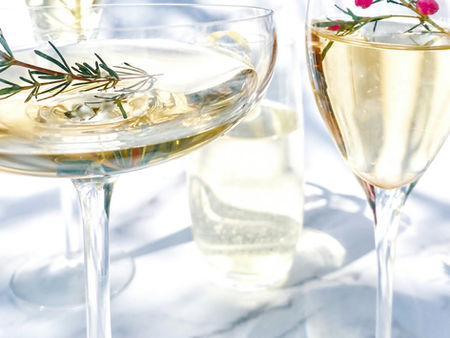 Een champagne flute, een coupe en een tulpglas met rozemarijn en roze bloemetjes
