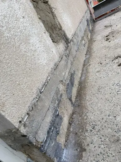 Stena pod oknom balkóna s odstráneným tehlovým obkladom, pripravená na rekonštrukciu