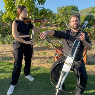 Live violin and cello duo performing at a luxury wedding ceremony in Los Cabos, Mexico