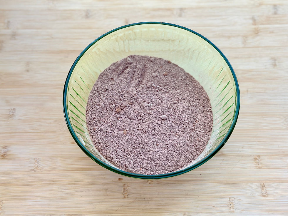 Glass bowl of dry baking ingredients combined for Gluten-Free Double Chocolate Banana Bread on a wooden countertop.