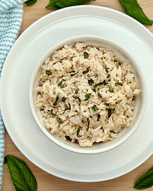 Fluffy cooked brown coconut rice mixed with finely chopped fresh basil in a white bowl