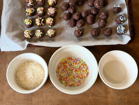 coconut, sprinkles, almond milk and a sheet tray of protein bites on a table