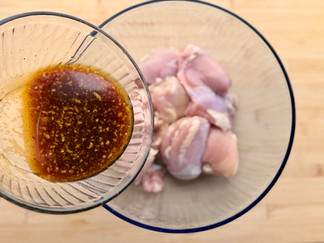 the honey garlic marinade pouring on the boneless chicken thighs