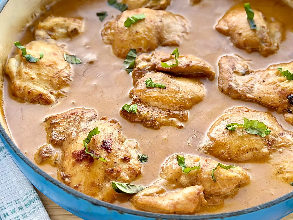Gluten-Free Creamy Coconut Lime Chicken pieces in creamy brown sauce, garnished with basil, simmering in a blue pan.