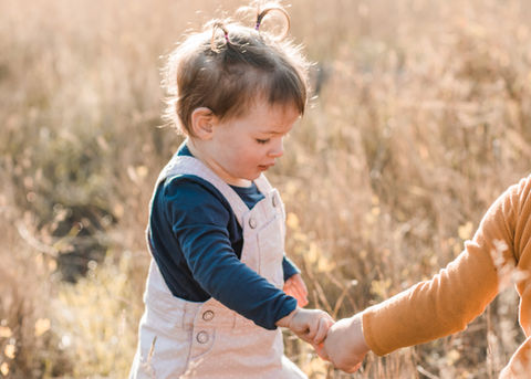 a young child leads their sibling by the hand for photos 