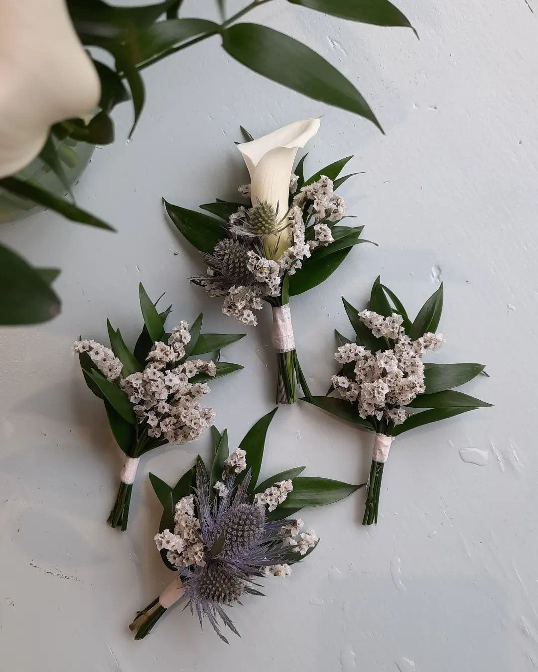 Boutonnières de mariage avec calla, limonium, ruscus et chardon