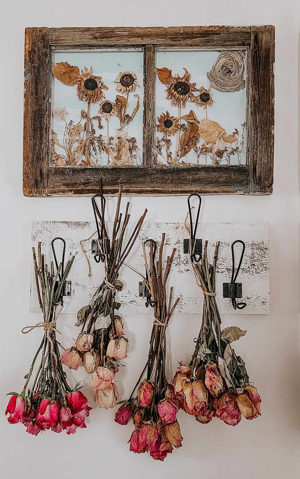 Dried roses hanging under a floral picture.