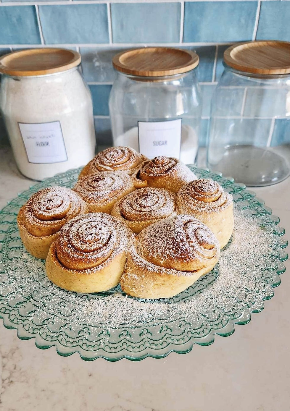 A plateful of lovely cinnamon buns on a pale blue cake platter.