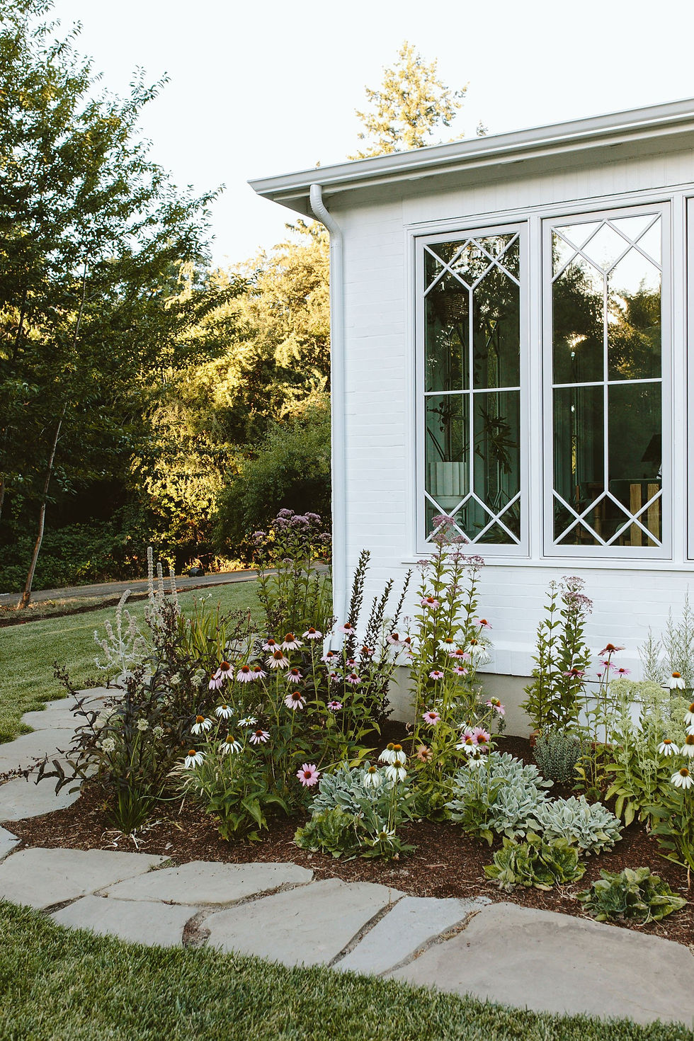A lovely white house with native plantings of echinacea and silvery plants.