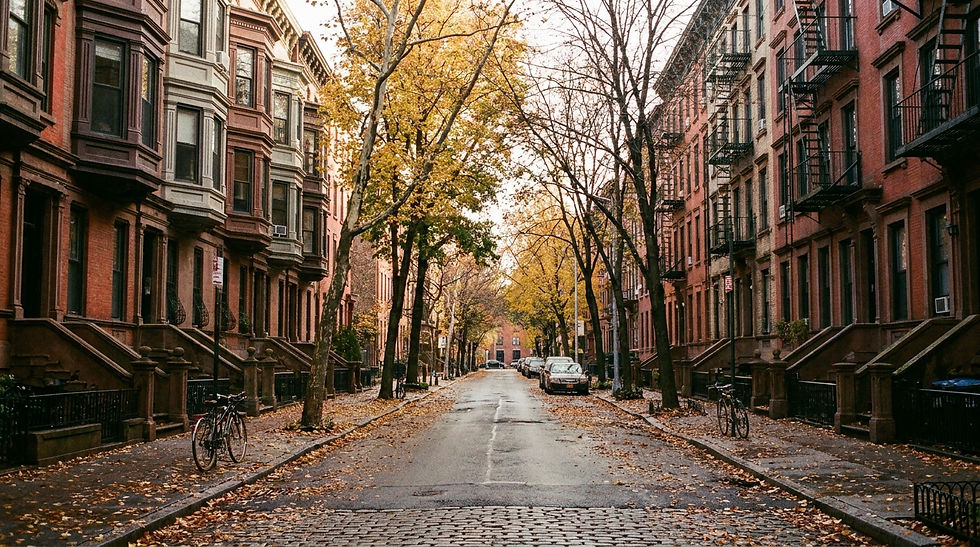Quiet autumn city street lined with brownstone buildings, bare and yellow-leaved trees, parked bikes and cars, calm mood
