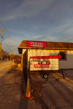 Vesuvio Pizza roadside sign and small building exterior along a busy street in Elkhart Indiana at sunset