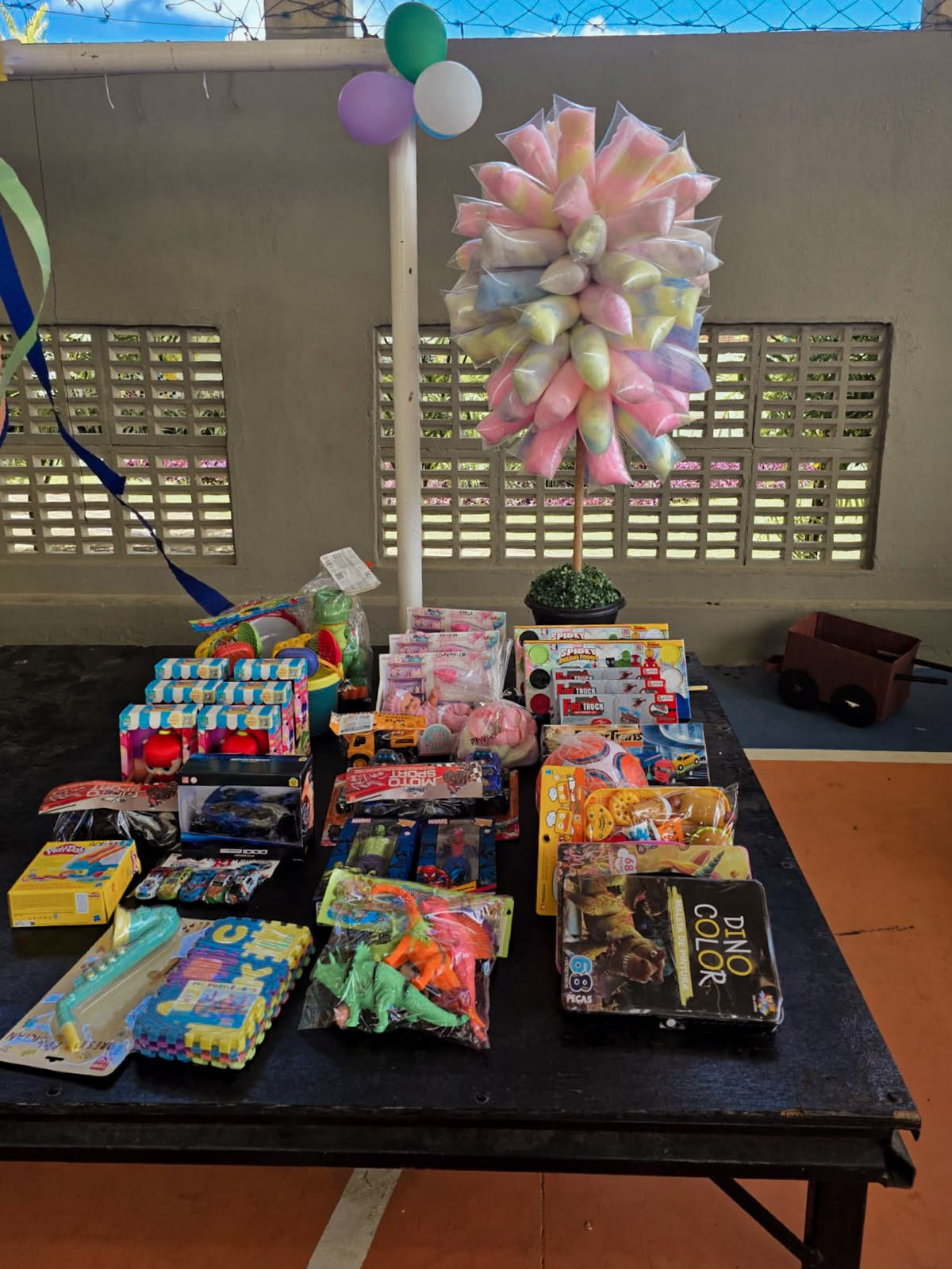 Mesa com brinquedos arrecadados para o Dia das Crianças e árvore de algodão-doce