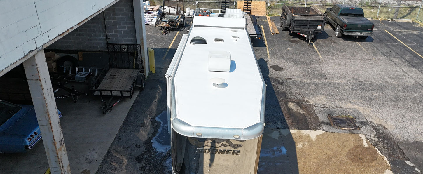White trailer parked in a loading area near tracks and loading docks.