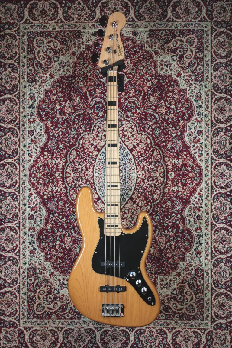 Front view of Squier Classic Vibe ‘70s Jazz Bass in Natural Gloss with black block inlays and black pickguard.