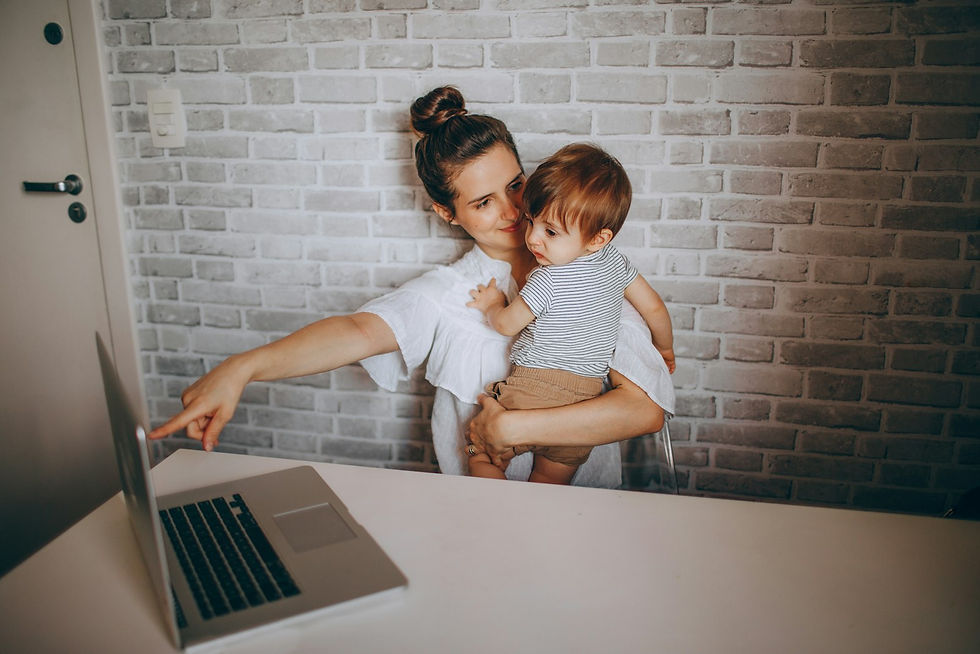 Mère portant son enfant devant un ordinateur portable, reprise du travail après un congé maternité