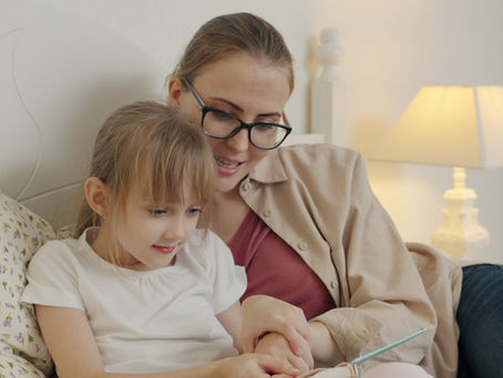 Mère aidant sa fille avec son cahier à la maison après l'école, charge mentale de la rentrée