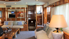 Luxury yacht interior saloon with wooden paneling, comfortable seating, and mirror accents.