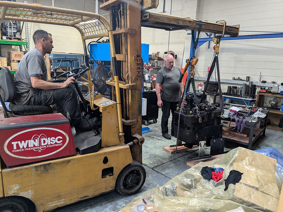 Men working on heavy machinery with a 'TWIN DISC' forklift
