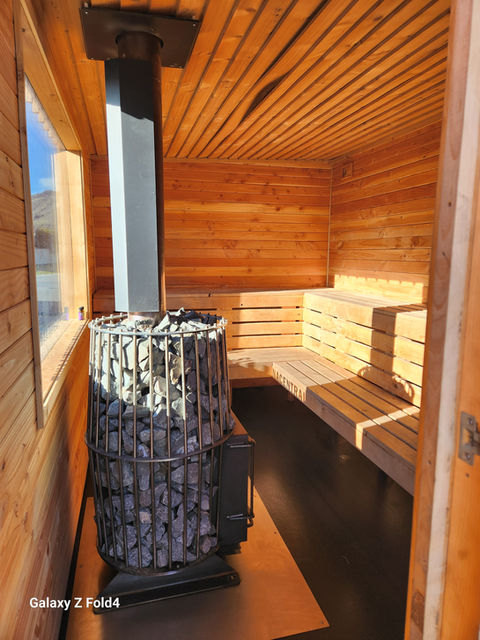 The interior of a wood-fired sauna by Sauna Central, showing a rock stove and wooden benches in Cromwell, New Zealand.