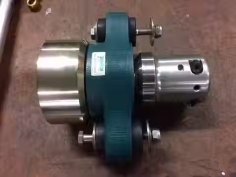 Top-down workshop view of a green-painted Aquadrive thrust bearing assembly mounted alongside a machined marine propeller shaft coupling.