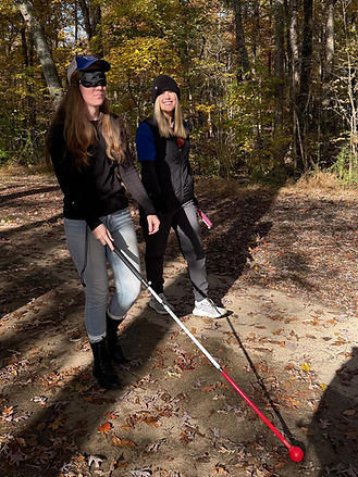 COMs instructor walks with adult peer using cane under blindfold