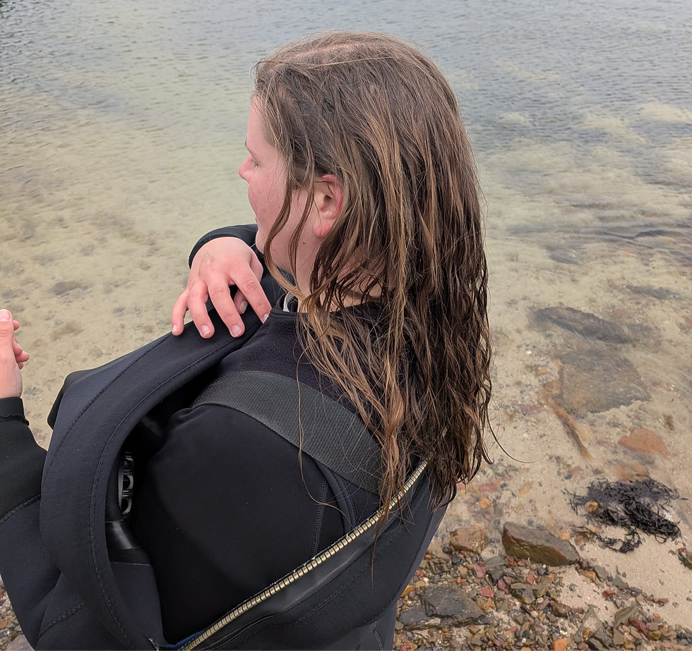 Instructor Margot with loose hair putting on her drysuit.