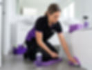 Spify operative scrubbing bathroom tiles on purple mat.
