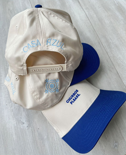Embroidered trucker hat natural and royal blue. Churros Please is embroidered on the front with the logo on the side and casa azul on the back of the hat. 