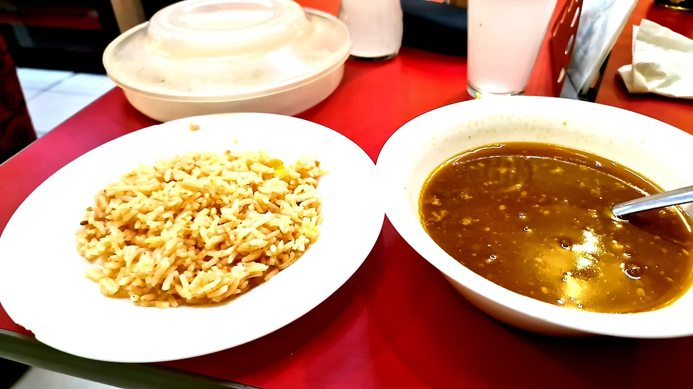 The many dishes on my table are tempting: rice, soups, beer.