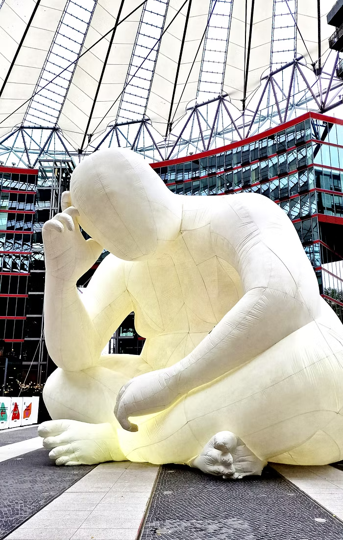 A giant seated inflatable figure sits enthroned under the roof of Potsdamer Platz.