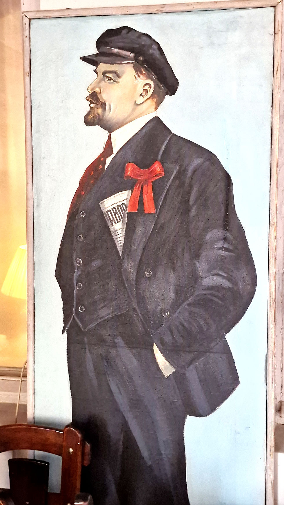 Mannshohes Seitenportrait eines freundlich schauenden Lenins in dunklem Anzug und roter Schleife.