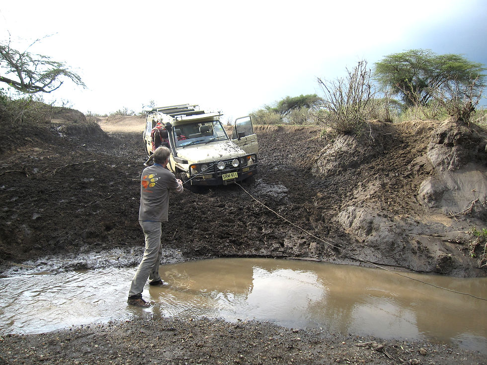 Bernd steht im Schlammwasser und zieht den im Schlammversunkenen Geländewagen heraus zu ziehen.