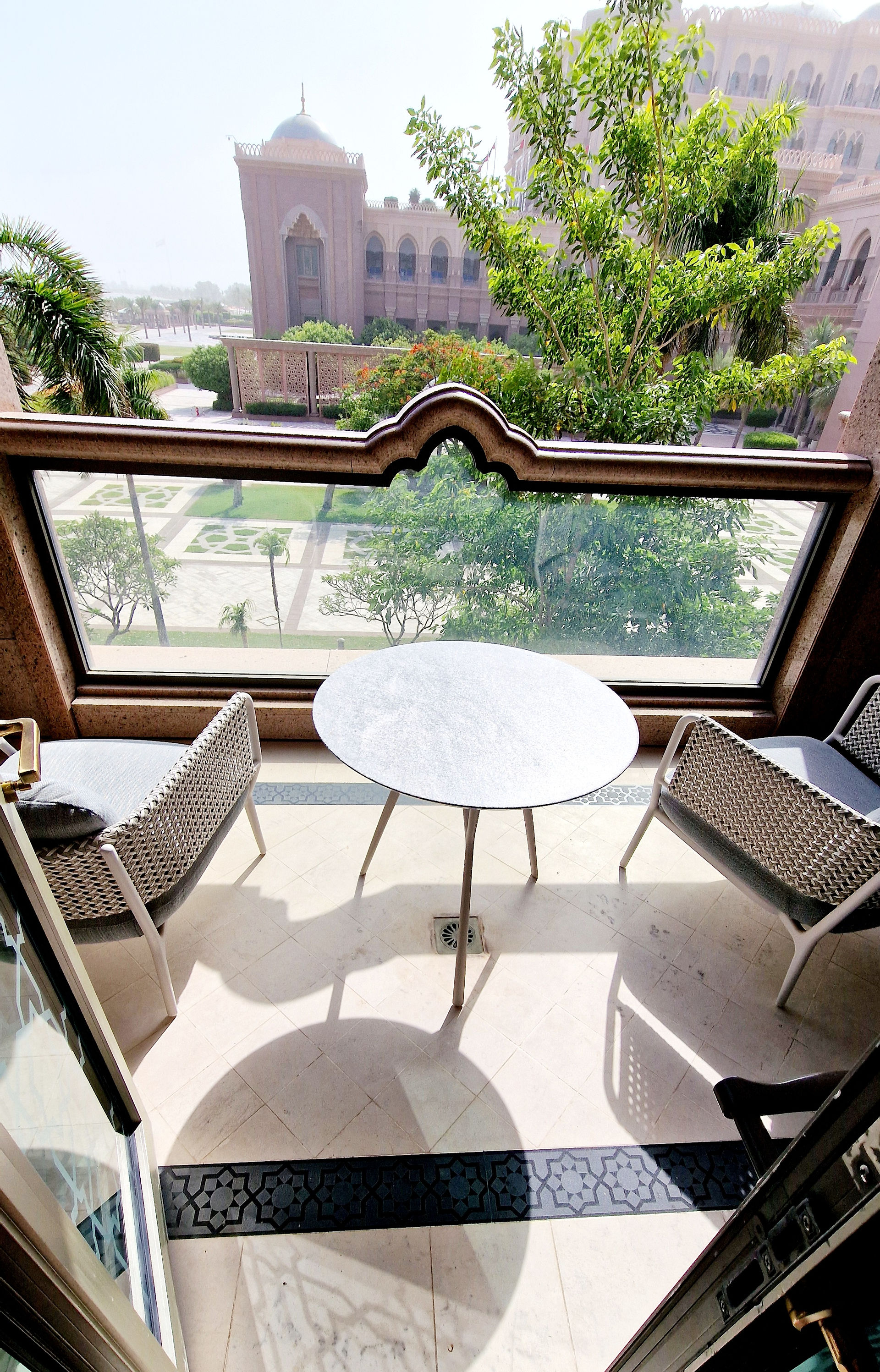 There are two comfortable armchairs and a round table on the balcony. The view is of the park.