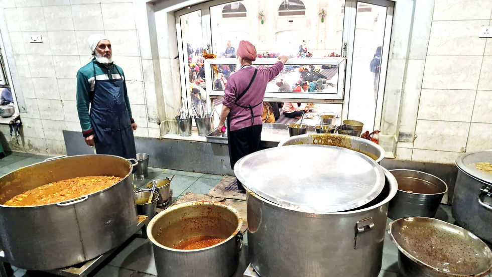 Zwei Männer in der Großküche eines Sikh -Tempels stehen vor großen Bottichen mit Nahrung.