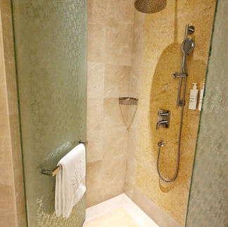 Die geräumige Dusche mit sandfarbenen Fliesen und Regendusche ist bereit.