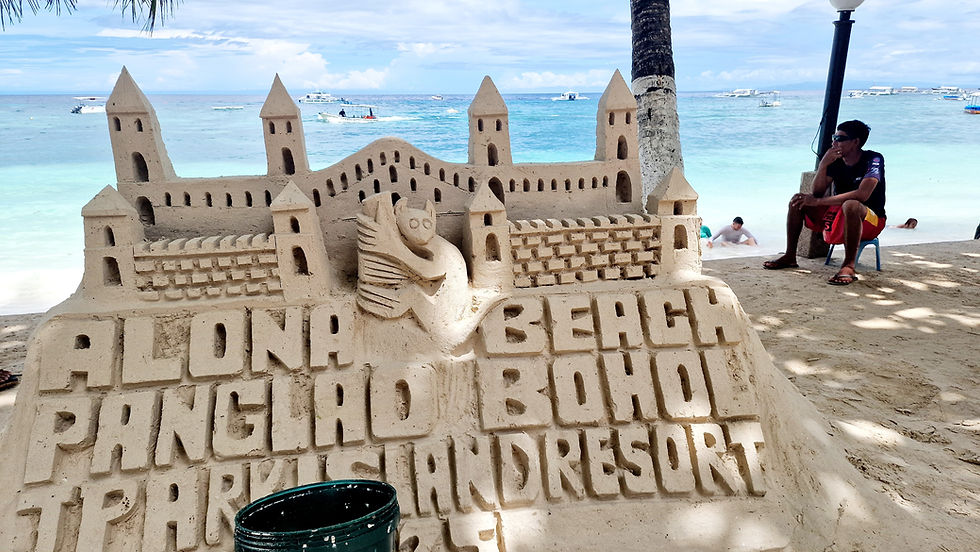 An artfully crafted sandcastle on the beach with the inscription: Alona Beach, Panglao Bohol.
