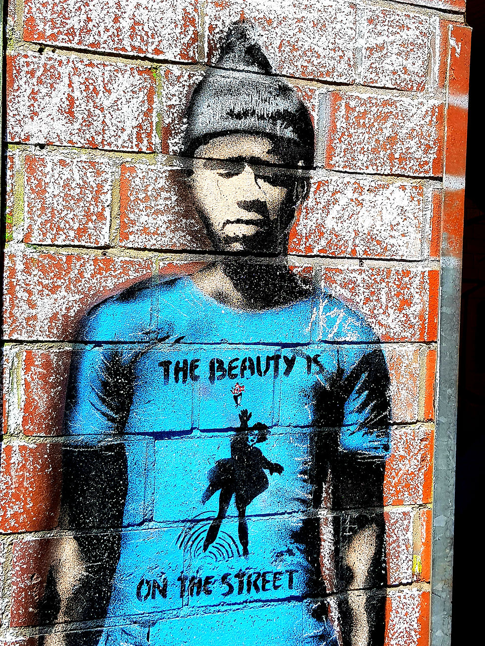 Graffiti of a person with dark skin. The blue T-shirt reads: The beauty is on the street.