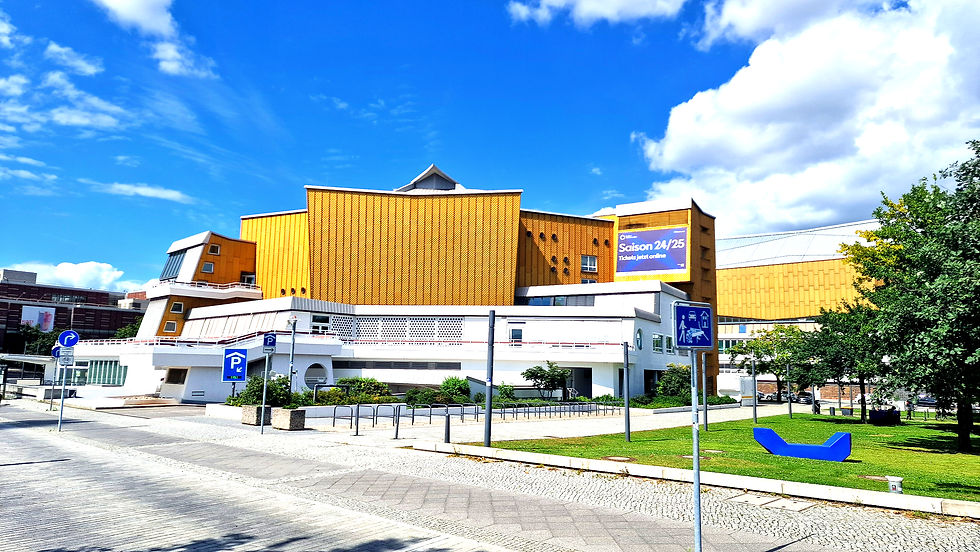 The golden yellow building of the Berlin Philharmonic shines against a blue sky.